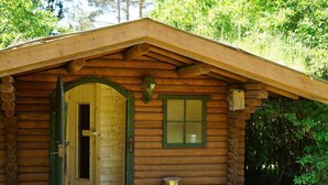 Une cabane en rondins avec une porte en bois et une fenêtre, entourée de verdure.