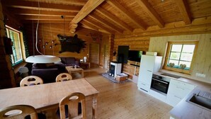 L’intérieur d’un chalet en bois rustique comprend un coin repas, une cuisine et un espace de vie.