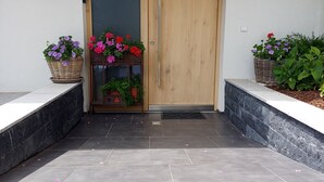 A modern entrance with a wooden door, a tiled floor, and potted plants on either side. - Cozy Apartment in Nature (Jochberg)