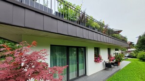 A modern two-story house with a balcony, large windows, and a well-maintained garden. - Cozy Apartment in Nature (Jochberg)