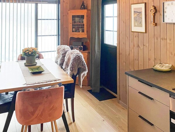 A wooden interior with a dining table, chairs, a cabinet, and a kitchen area. - 4 Star Holiday Home in Passebekk (Kongsberg)