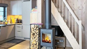 A modern kitchen with a wood-burning stove, a dining area, and a staircase. - 4 Star Holiday Home in Passebekk (Kongsberg)