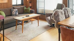 A cozy living room with a wooden floor, a sofa, a coffee table, and a chair with a furry throw. - 4 Star Holiday Home in Passebekk (Kongsberg)