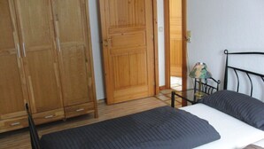 A bedroom with a bed, a wooden wardrobe, and a nightstand with a lamp. - Karlo 4 Modern Retreat (Büsum)