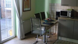 A small kitchen with a dining table, chairs, a microwave, and a radiator. - Karlo 4 Modern Retreat (Büsum)