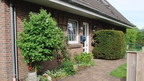 A brick house with a paved driveway, a mailbox, and a well-maintained garden with various plants and flowers. - Karlo 4 Modern Retreat (Büsum)