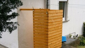 Un étendoir en bois fixé au mur extérieur d’un bâtiment.