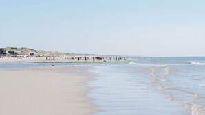 A beach with a sandy shore and a building in the background. - Oceanhouse Comfortable Holiday Residence (Wieringerwerf)