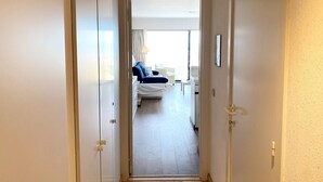 A hotel hallway leading to a bedroom with a bed, a nightstand, and a lamp. - Apartment in Nieuwpoort With Garden (Nieuwpoort)