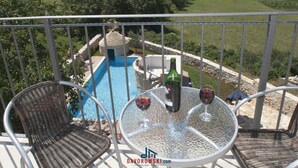 Ein Balkon mit einem Glastisch, zwei Korbstühlen, einem kleinen Pool und einer Steinstruktur.