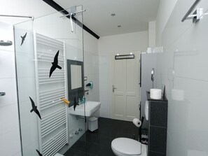 A modern bathroom with a glass shower enclosure, a white toilet, a sink, and a mirror. - Fischer 2 Modern Retreat (Zinnowitz)