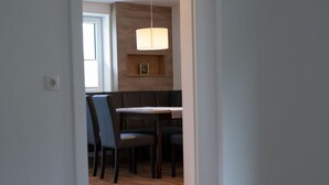 A dining area with a table and chairs, a hanging light fixture, and a wooden wall. - Apartment Bar Comfortable Holiday Residence (Eben im Pongau)
