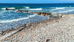 A pebbled beach with waves crashing onto rocks. - 6 Person Holiday Home in Graested (Graested)