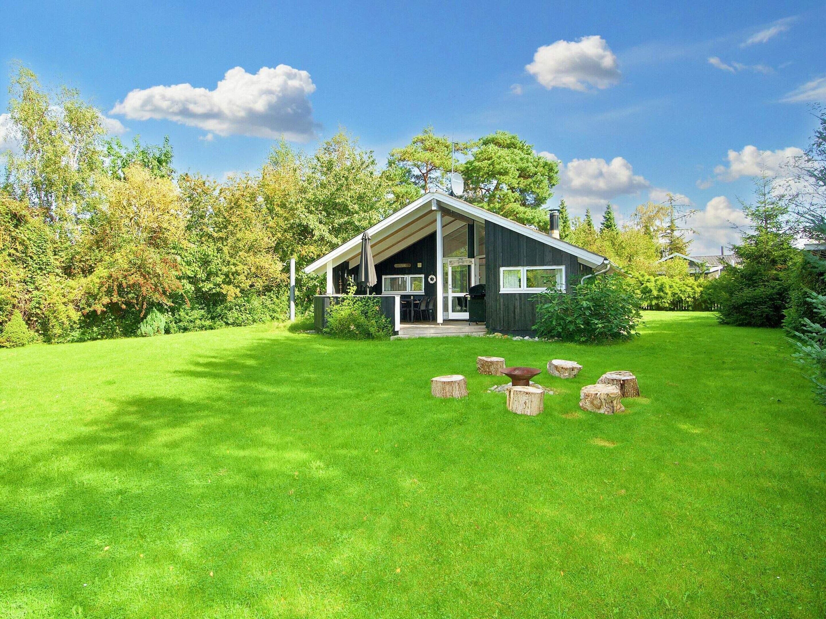 A modern house with a covered porch, surrounded by a well-maintained lawn and trees.