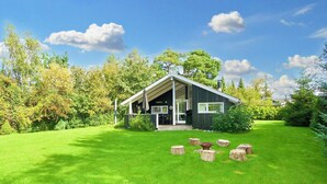 A modern house with a covered porch, surrounded by a well-maintained lawn and trees. - 6 Person Holiday Home in Graested (Graested)