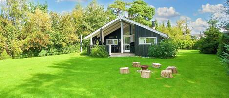 A modern house with a covered porch, surrounded by a well-maintained lawn and trees.