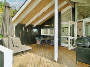 A covered outdoor patio with a table and chairs, a grill, and a covered seating area. - 6 Person Holiday Home in Graested (Graested)