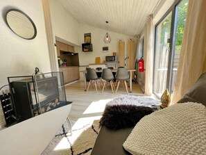 Una sala de estar moderna con un sofá, una mesa de centro y un televisor. Hay una zona de cocina con una mesa de comedor y sillas.
