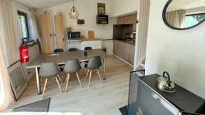 A compact kitchen with a dining area, wooden cabinets, a microwave, and a kettle on a counter.