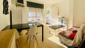Un espacio habitable compacto con una mesa de comedor, un sofá, un televisor y vistas al exterior.