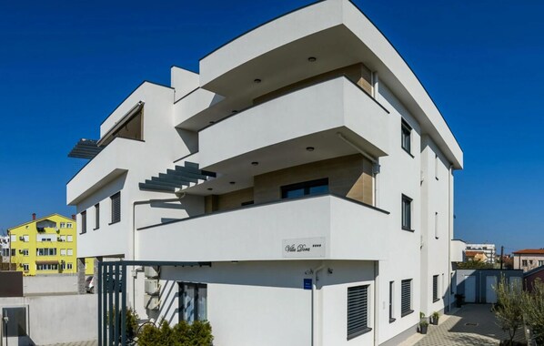 Um edifício moderno de vários andares com varandas, uma escadaria e uma placa com a inscrição 