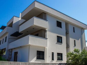 Um edifício moderno de vários andares, com varandas, janelas amplas e telhado plano.