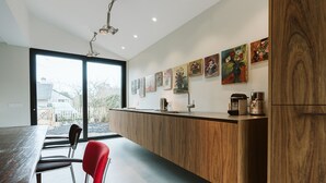 A modern kitchen with a wooden countertop, red chairs, and a dining table. - Holiday Home for Family (Ouddorp)