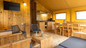 Un acogedor interior de cabaña con paredes de madera, comedor, cocina y zona de descanso.