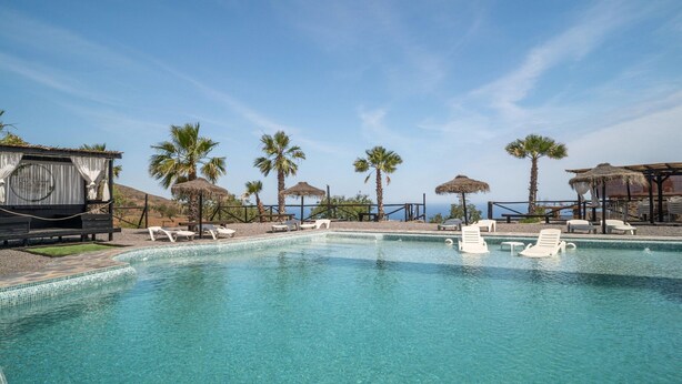 A clear blue pool with lounge chairs and palm trees, surrounded by wooden structures and a clear sky. - Villa Near Adra With Sea and Mountain Views (Adra)
