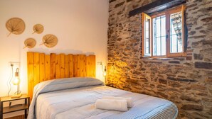 A bedroom with a wooden headboard, a stone wall, and a window with curtains. - Villa Near Adra With Sea and Mountain Views (Adra)