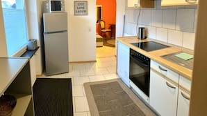 Eine kompakte Küche mit Kühlschrank, Mikrowelle, Herd und Backofen. Ein Schild mit der Aufschrift 'LIVE LOVE LAUGH'.