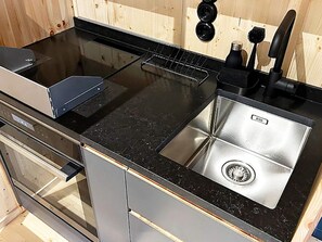 Eine Küche mit schwarzem Arbeitsplatz, Edelstahlspüle und einem eingebauten Backofen.