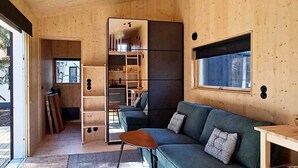 A modern interior with a wooden floor, a green sofa, a small table, and a window.