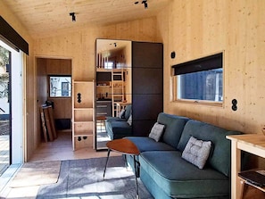 Ein modernes Interieur mit Holzboden, einem grünen Sofa, einem kleinen Tisch und einem Fenster.