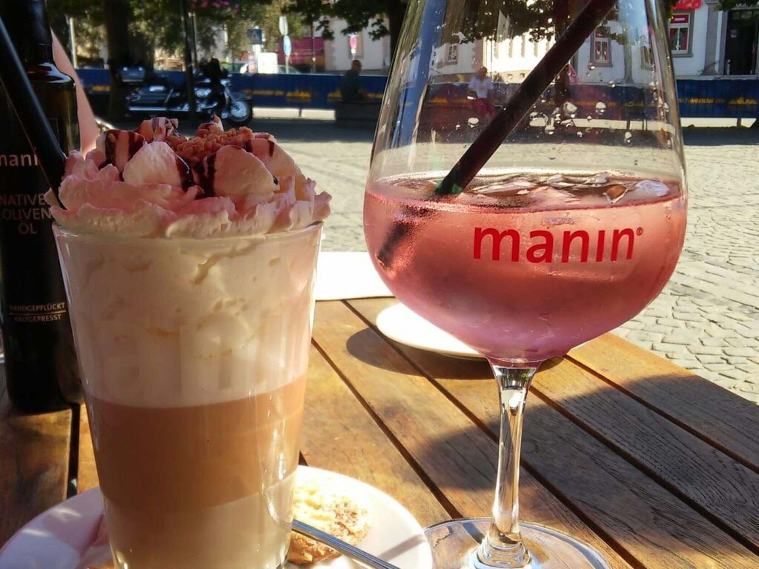 Two drinks on a wooden table outdoors.