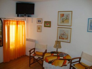 Cozy living room with a flat-screen TV, dining table, and artwork on the walls.