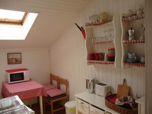 Enjoy meals around the central dining table in this cozy kitchen, equipped with a microwave, toaster, and sink.
