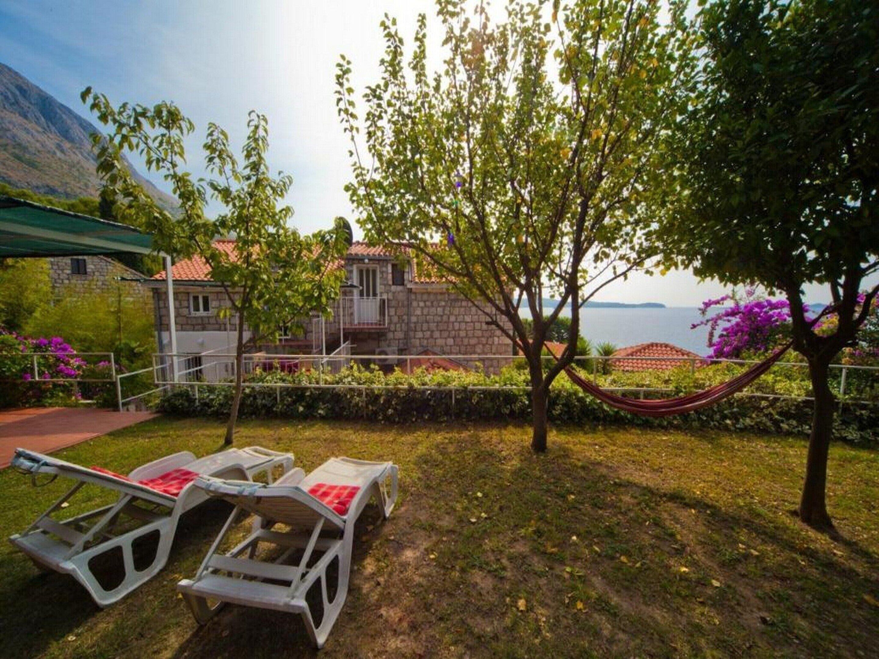 Une villa avec une façade en pierre, un hamac et une vue sur la mer.