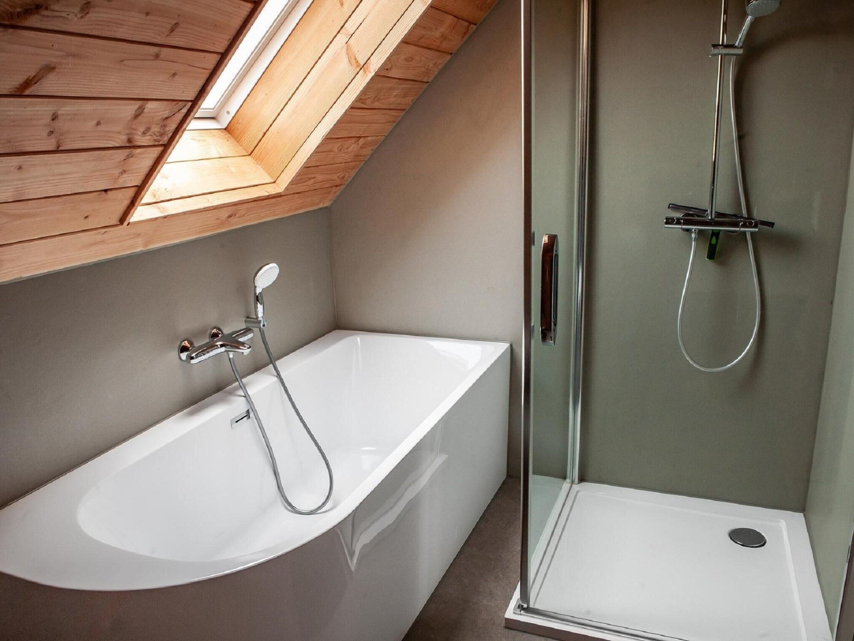 A modern bathroom with a skylight, a freestanding bathtub, and a glass-enclosed shower.