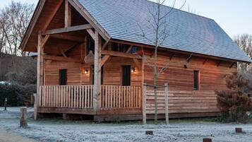 A wooden cabin with a porch, a sloped roof, and a small window.