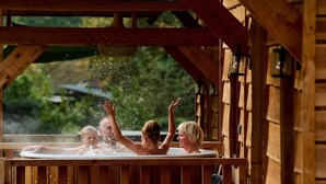 A wooden cabin with a hot tub where people are enjoying water play. - Holiday Home in Brabant With Private Spa (Uden)