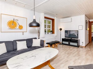 A living room with a sofa, a marble coffee table, a television, and a pendant light.