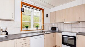 Una cocina moderna con lavavajillas, microondas, horno y ventana con plantas.