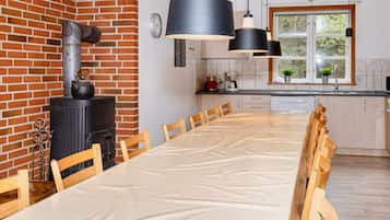 A modern kitchen with a brick wall, a stove, and a dining area with a long table and chairs.