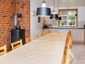 A modern kitchen with a brick wall, a stove, and a dining area with a long table and chairs.