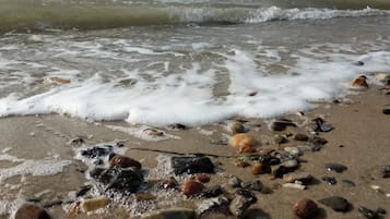 A beach with waves, pebbles, and shells.