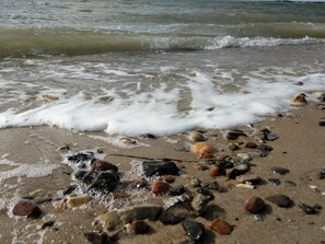 A beach with waves, pebbles, and shells.