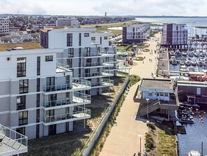 Een modern gebouw met meerdere balkons, een jachthaven met boten, en vrij uitzicht op het water.