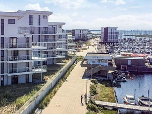 A waterfront residential area with modern buildings, a marina, and a pedestrian walkway.