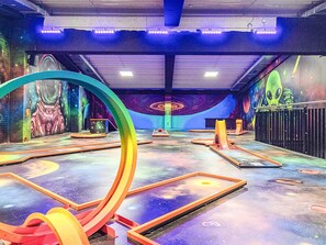 Een ruimte binnenshuis met een futuristisch ontwerp, met een grote ronde constructie, een muurschildering met ruimtethema en een centrale kolom.